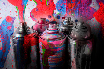 Multi-colored aerosol paints on a dirty gray background with stains of paint.