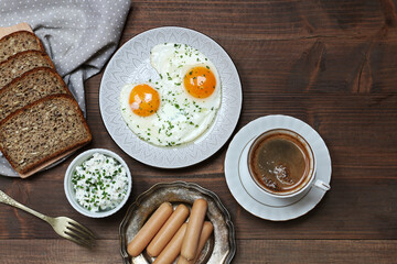 Plate with fried eggs, bread and bowl with cottage cheese on brown wooden table