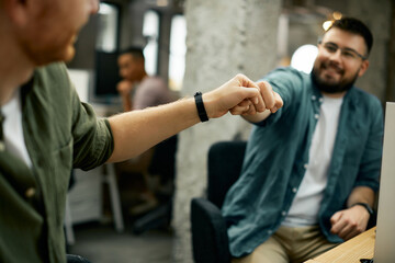 Close-up of business colleagues fist bumping in the office.