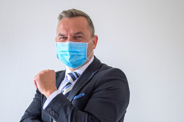 Businessman wearing a suit and face mask giving a greeting
