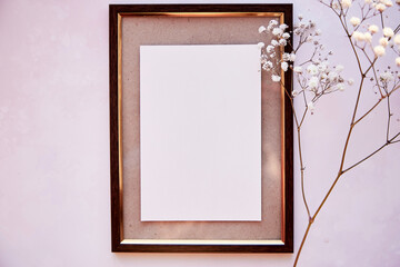 Brown frame mockup on vintage surface. Vintage frame with gypsophila. Beige background, Scandinavian interior. Top view. Place for advertising, thank you or wishing.