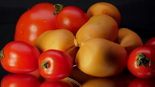 Cherry tomatoes and brown bangers bunch lie on black glass table reflecting on surface in kitchen. Concept health nutrition