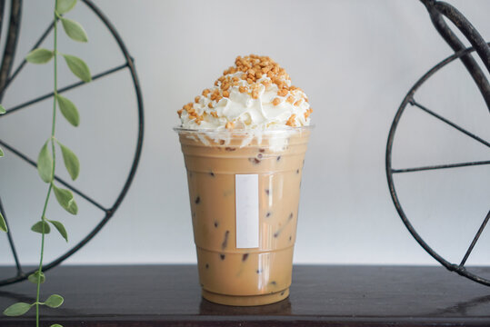 Iced Hazelnut coffee latte topped with whipping cream and crispy almond.