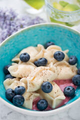 Close-up of cottage cheese dumplings with bilberries served in a turquoise bowl, selective focus