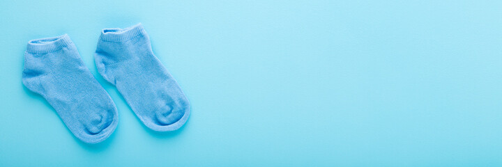 Kid short socks on light blue table background. Pastel color. Closeup. Clothes wide banner. Empty place for text. Top down view.