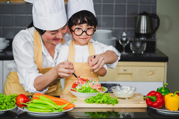  Asian woman young mother with son boy cooking salad mom sliced vegetables food son tasting salad dressing vegetable carrots and tomatoes bell peppers happy family cook food enjoyment lifestyle 