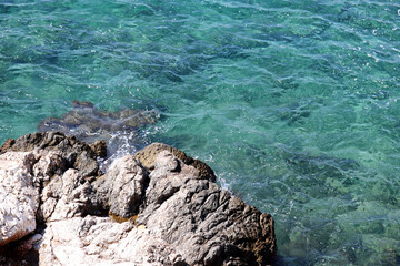 Rock and clean azure water on a beach. Coast of Mediterranean sea