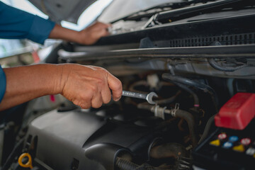 Hand of an auto mechanic is repairing the problematic car. Car service and maintenance concept.