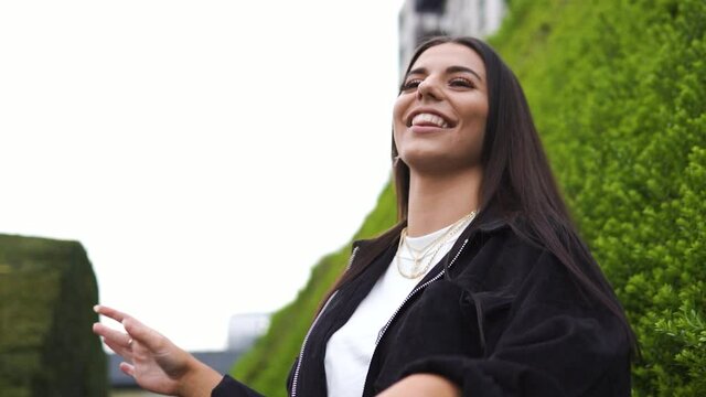 Brunette positive female in nature laughing genuine smiling fashionable wearing jewellery gold silver blurry backround good times slow motion
