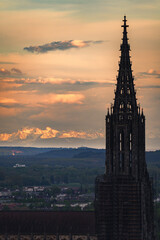Obraz premium Sunset Panorma Mountain range alps with city ulm and ulmer minster take from a far distance at sunrise sunset dramatic spring sky and blooming tree