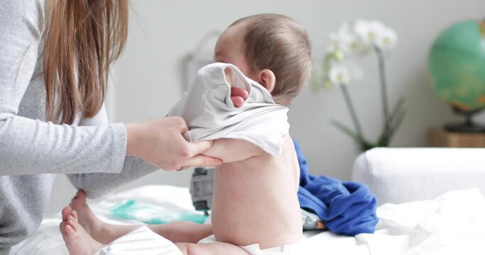 Young mother getting her baby boy dressed