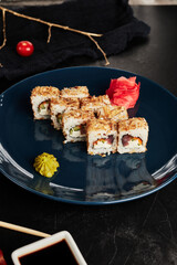 rolls with tuna shavings on a blue plate on a black textured background