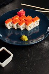 rolls in caviar on a blue plate on a black textured background