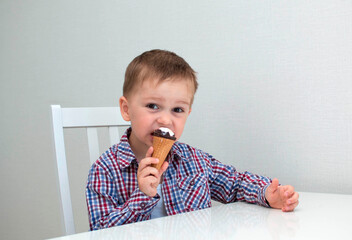 Happy attractive baby licking or eating chocolate ice cream in a cone.