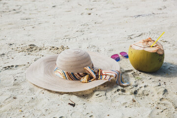 Summer hat and sunglasses with coconut fruit on the beach sand