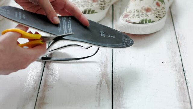 Woman's hands hold orthopedic insoles for shoes, comparing them with each other. Side view. Close up.