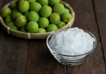 Unripe plums and rock candy on a wooden background.