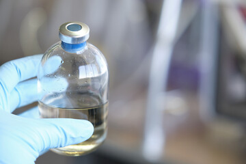 Researcher hand wearing gloves holding a bottle for anaerobic cultures, with cap and septum....
