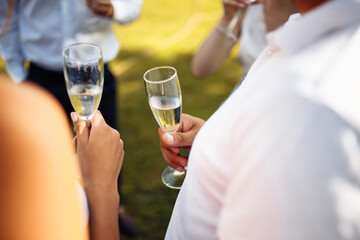 Wedding guests clinking glasses. Group of people enjoying champagne at wedding party. Guests toasting and cheering at stylish celebration.