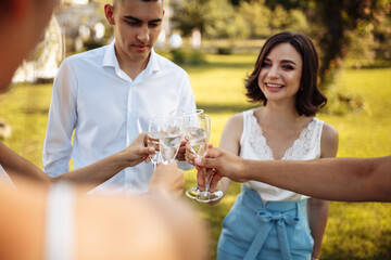 Wedding guests clinking glasses. Group of people enjoying champagne at wedding party. Guests toasting and cheering at stylish celebration.