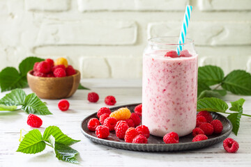 Summer cool milkshake. Raspberry protein shake in glass and fresh raspberry on a wooden table. Copy space.