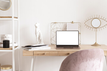 Laptop with blank screen mock-up, interior still life concept. Elegant and trendy working space on wooden table. Feminine working space, home office. Living room interior design with workplace.