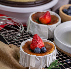 Burnt Cheese Cake, Basque Cheesecake with strawberry and blueberry toppings on Parchment Paper, close-up