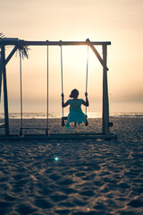 Young attractive woman with pink hair swinging on seesaw on the beach.