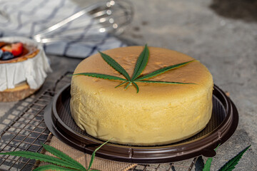 Japanese Cheese Cake with cannabis leaf topping on grey background. - obrazy, fototapety, plakaty