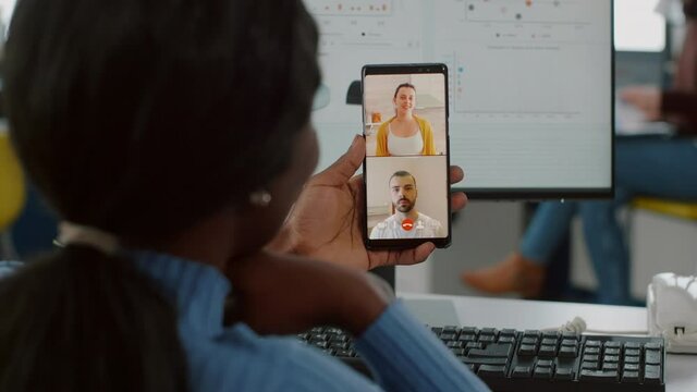 Handicapped invalid african manager talking on videocall with friends holding mobile working at financial project of company , taking break during work time. Employee sitting immobilized in wheelchair