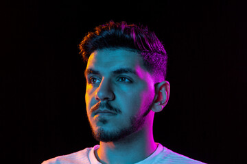 Young man's portrait on black studio background in neon light. Concept of human emotions, facial...