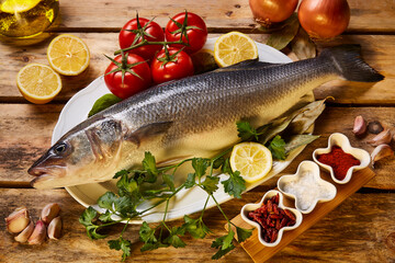 fish on a tray with garlic, lemons, spices, tomatoes