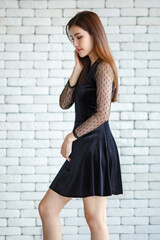 Smiling elegant woman in dress on brick wall background