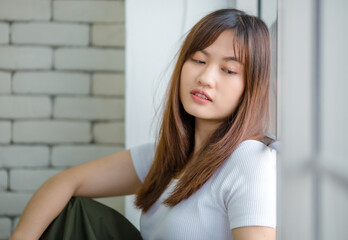 Thoughtful Asian woman looking out of window at home