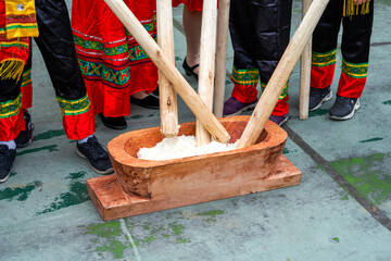 A group of people hammering glutinous rice with wooden sticks for making rice cakes with characteristics of Guangxi Zhuang nationality