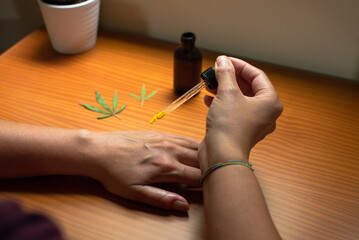 Woman pouring CBD oil on her hand. CBD extract, natural skin care product made with marijuana.