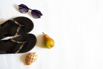Summer vacation on the beach, shell, headphones, flip-flops, sunglasses and pear, flat lay on white background