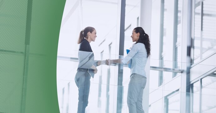 Abstract technology background against two businesswomen shaking hands at office