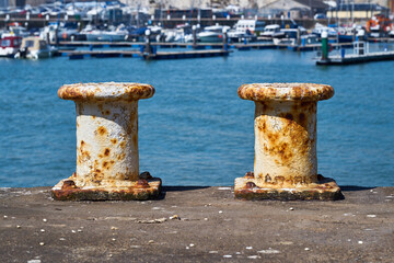 Two pillar bollards for mooring boats with the harbour in the background
