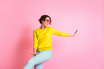 Fototapeta na wymiar Photo of young attractive lovely girl in funky glasses dancing wear yellow sweater blue pants isolated on pink color background
