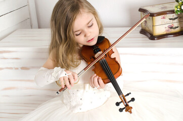 Girl playing violin with pleasure. Copy space. Close-up. Wooden background.
