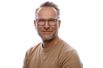 Smiling friendly unshaven middle-aged man in leisurewear wearing glasses turning to look at the camera in an upper body portrait on white