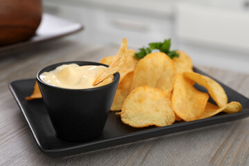 Potato chips and mayonnaise on wooden table, space for text