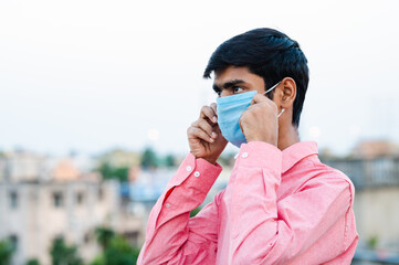 Portrait of young Indian man wearing surgical mask for protection from harmful virus and pollution