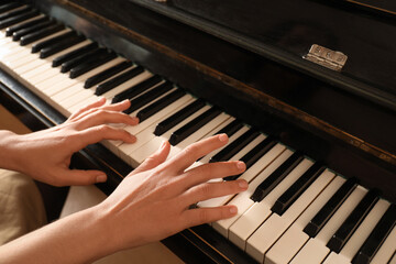 Fototapeta premium Young woman playing piano, closeup. Music lesson