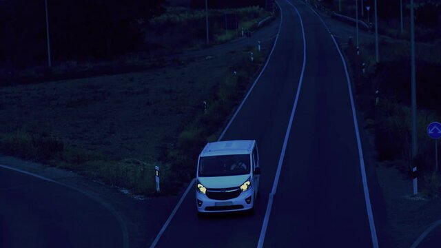 Aerial view of a white delivery van driving on the road in the evening