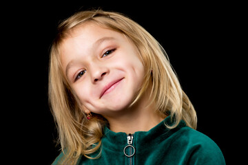 Close up view of a cute smiling little girl posing on black background.