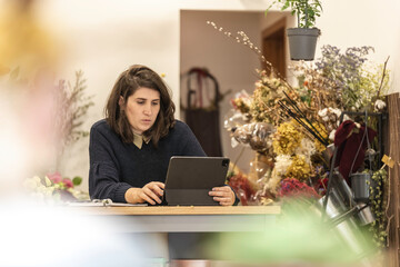 View of a young businesswoman working as florist looking at her laptop, young entrepreneurs concept. - obrazy, fototapety, plakaty