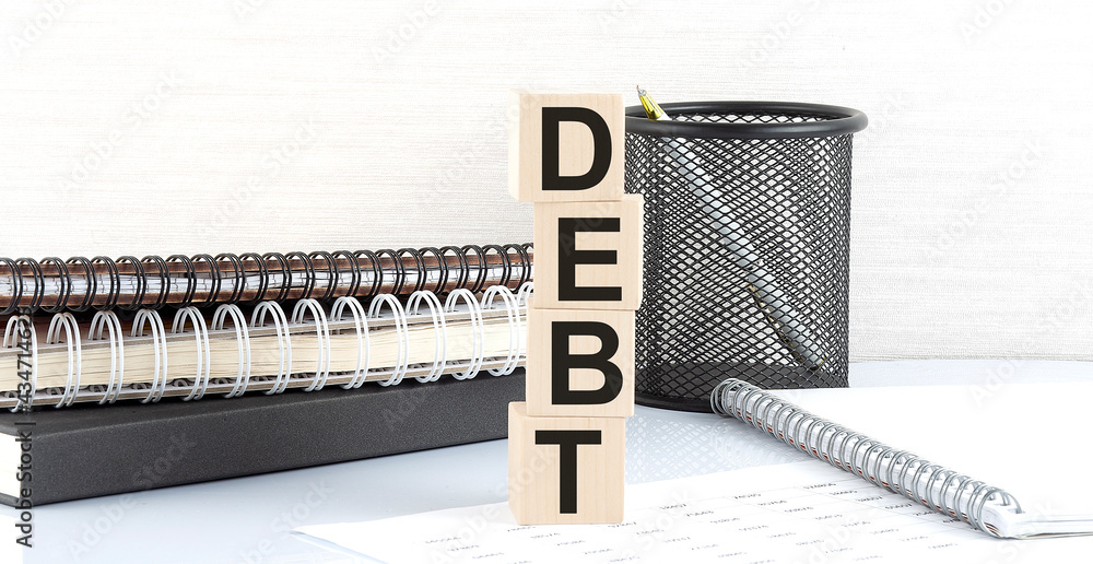 Poster debt text on wooden block with notebooks on white background
