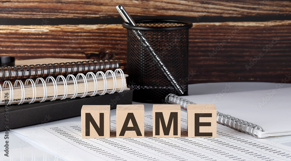 Aufkleber name text on wooden block with notebooks on chart